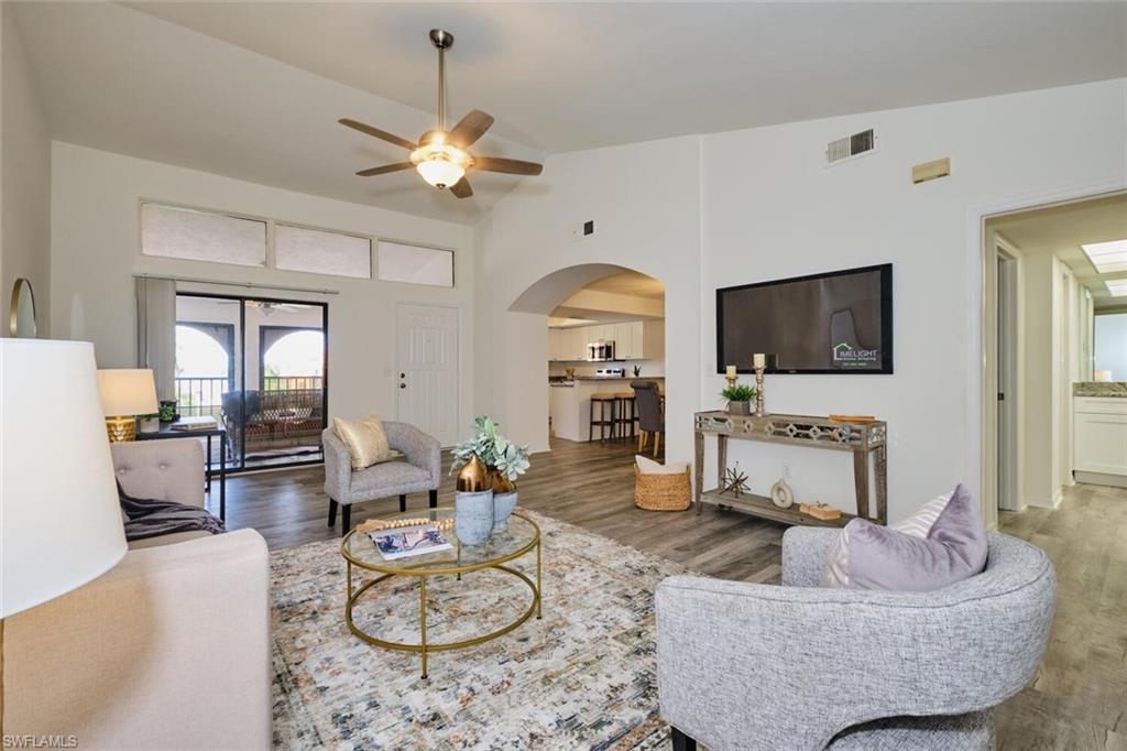 Spacious living area featuring vaulted ceilings, wood-finish flooring, and an arched doorway