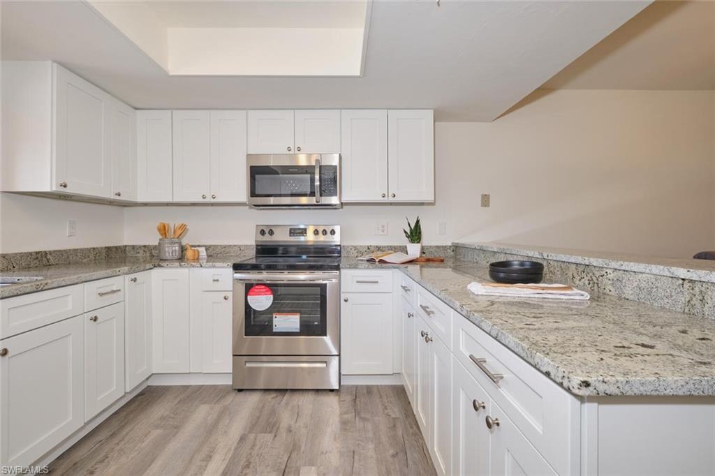 U-shaped kitchen featuring white cabinetry, stainless steel range and microwave