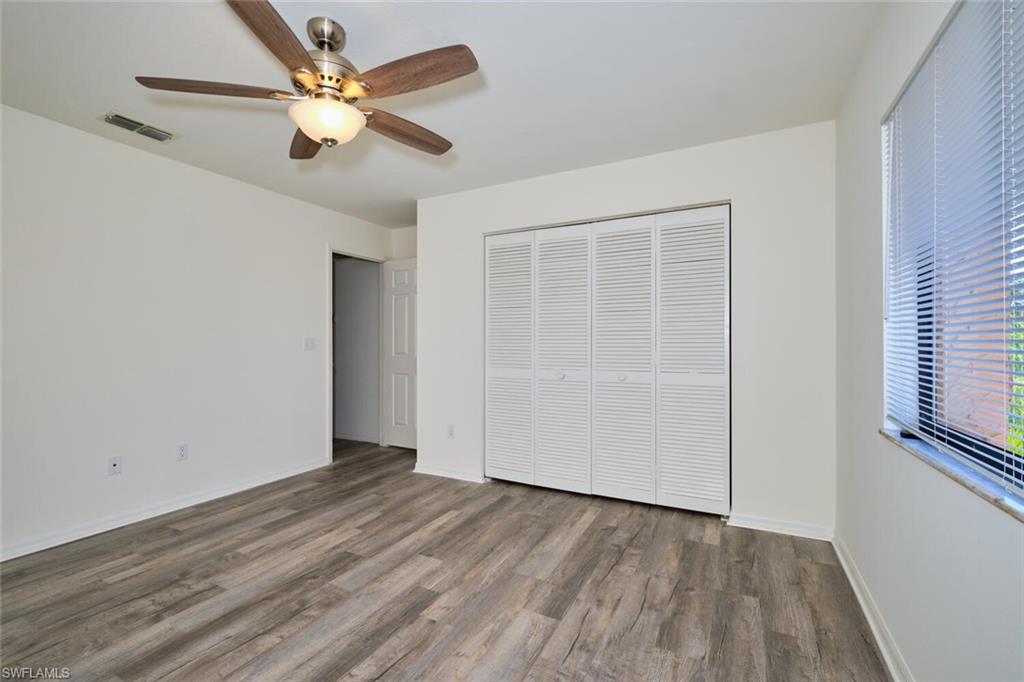 Spacious interior featuring wood-finish flooring, white walls, and a ceiling fan with integrated lighting