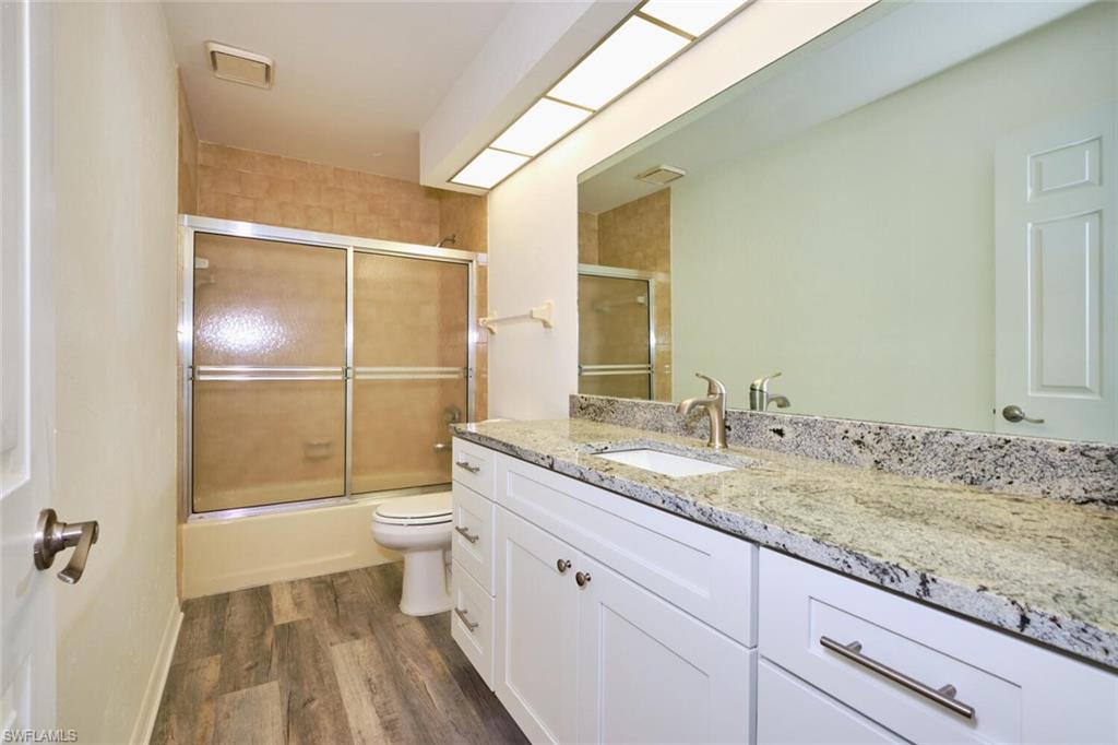 Bathroom featuring a white vanity with shaker-style cabinetry, a speckled countertop, an undermount sink, and a large mirror