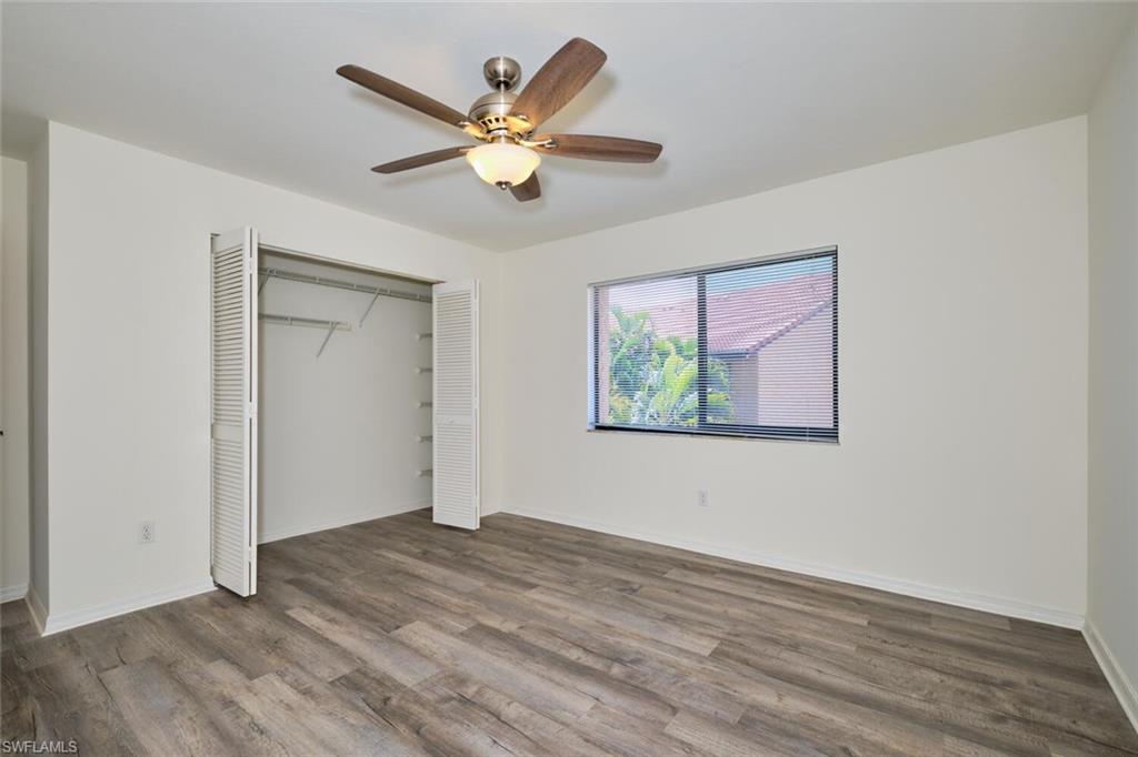 Room featuring wood-finish flooring, a ceiling fan with integrated lighting, a louvered bi-fold closet, and a horizontal window with blinds