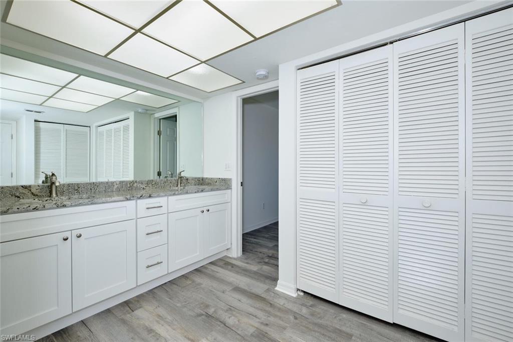 Bathroom featuring a double vanity with granite-style countertop, dual sinks, and under-sink cabinetry