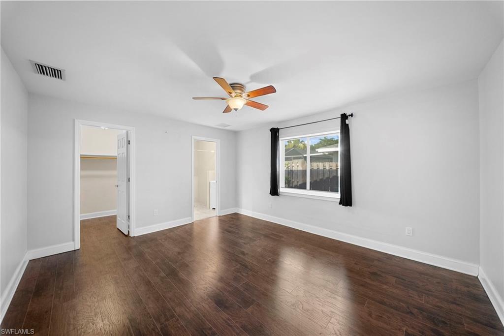 Spacious room featuring wood-finish flooring, a ceiling fan, and a large window
