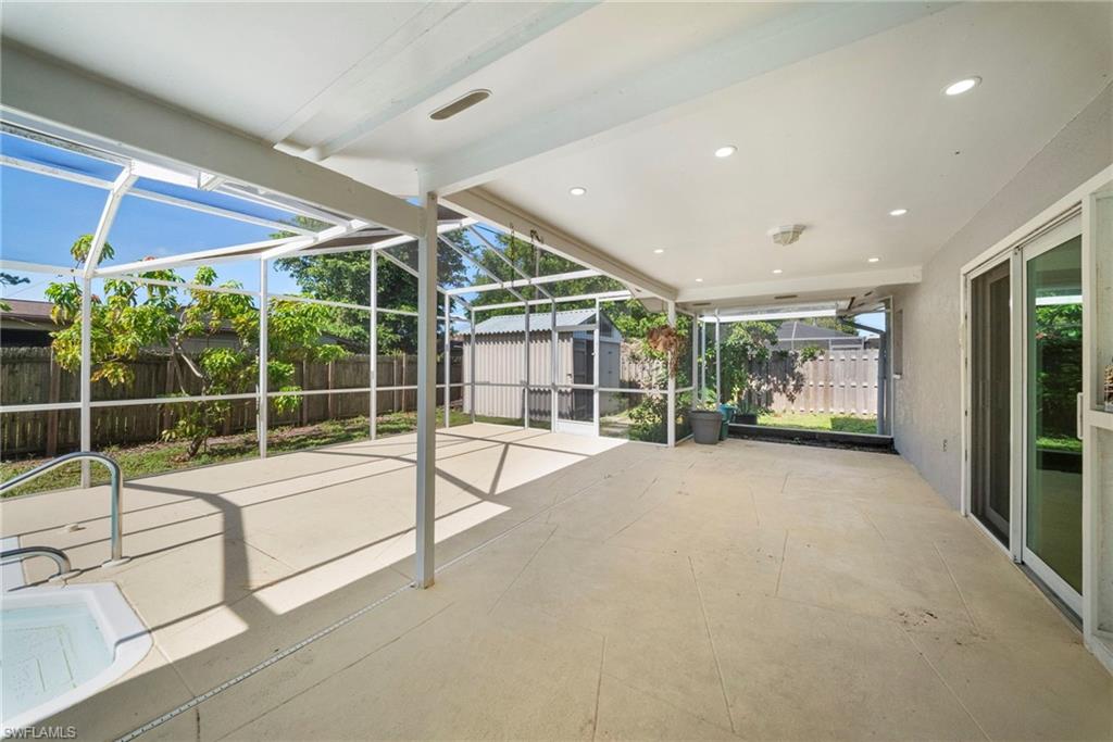 Expansive screened patio featuring textured concrete flooring, a built-in spa, recessed lighting, and direct access to the interior via sliding glass doors