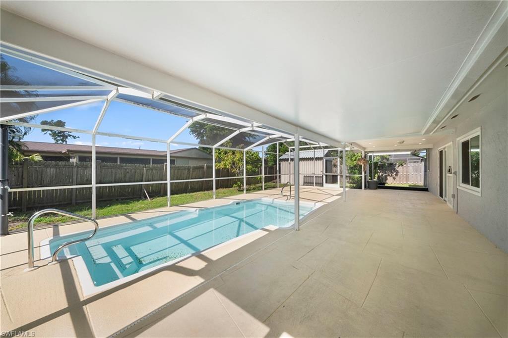 Screened enclosure featuring an in-ground swimming pool with steps, a covered patio area with light-toned flooring, and a solid roof extension
