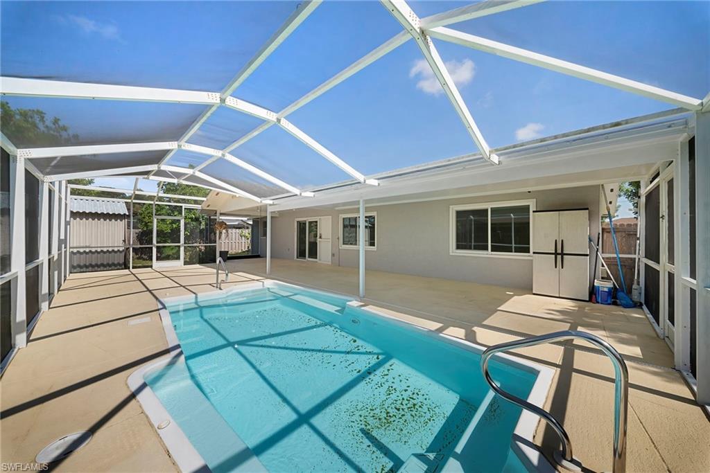 Screened-in swimming pool with concrete decking, featuring a white aluminum frame enclosure and direct access to the interior via sliding glass doors