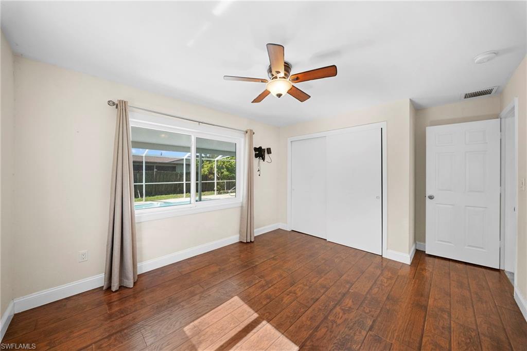 Room featuring wood-finish flooring, a ceiling fan with integrated lighting, and a large window