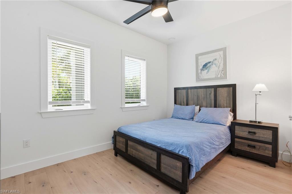 Bright interior space featuring light wood-finish flooring, white walls, and two windows with white blinds
