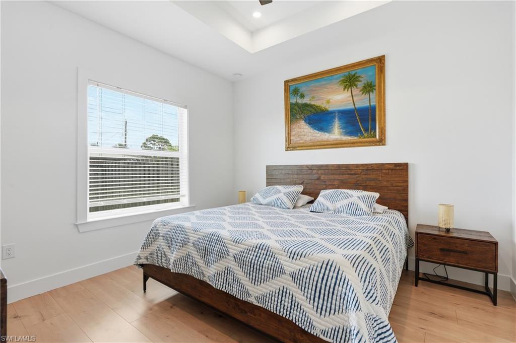 Bedroom featuring light wood-finish flooring, white walls, and a large window with blinds