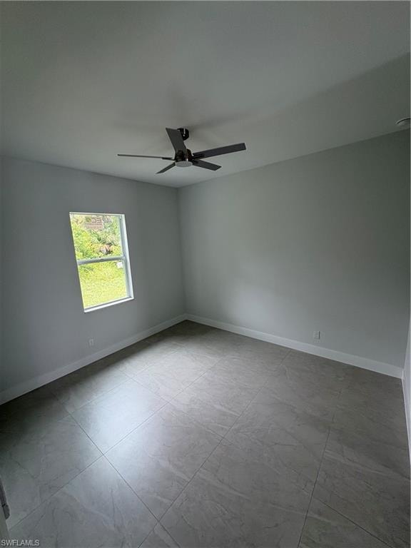 Neutral-toned room featuring large format tile flooring, a modern ceiling fan, and white baseboards