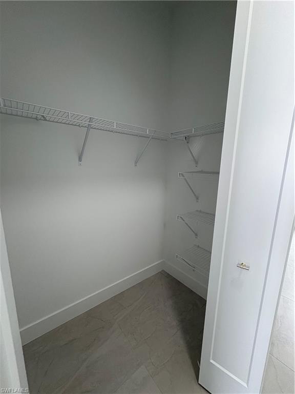 Walk-in closet featuring white wire shelving, white baseboards, and tile flooring