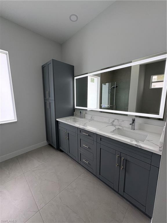 Bathroom featuring a dual vanity with gray cabinetry, integrated sinks, and white countertops