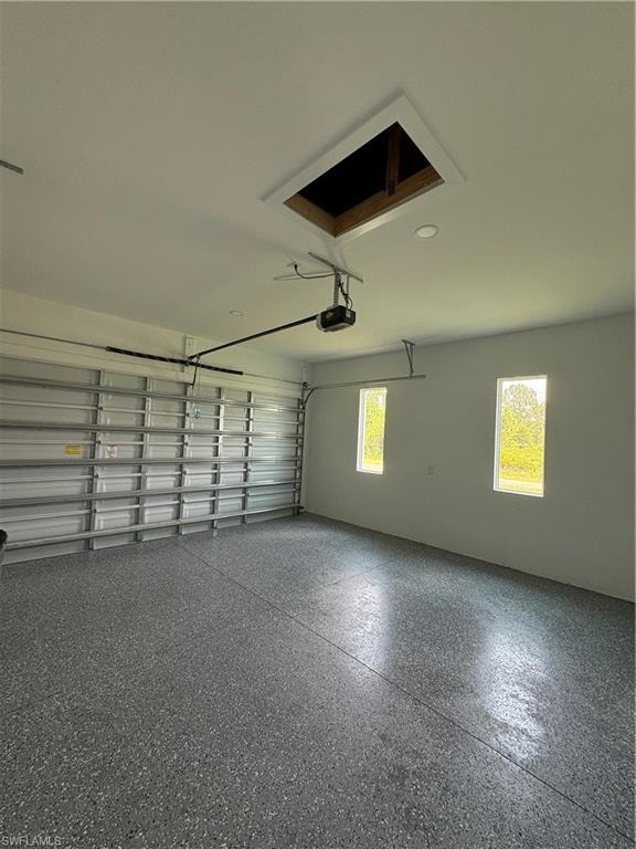 Garage featuring a textured gray epoxy floor, automatic garage door opener, recessed lighting, and two rectangular windows