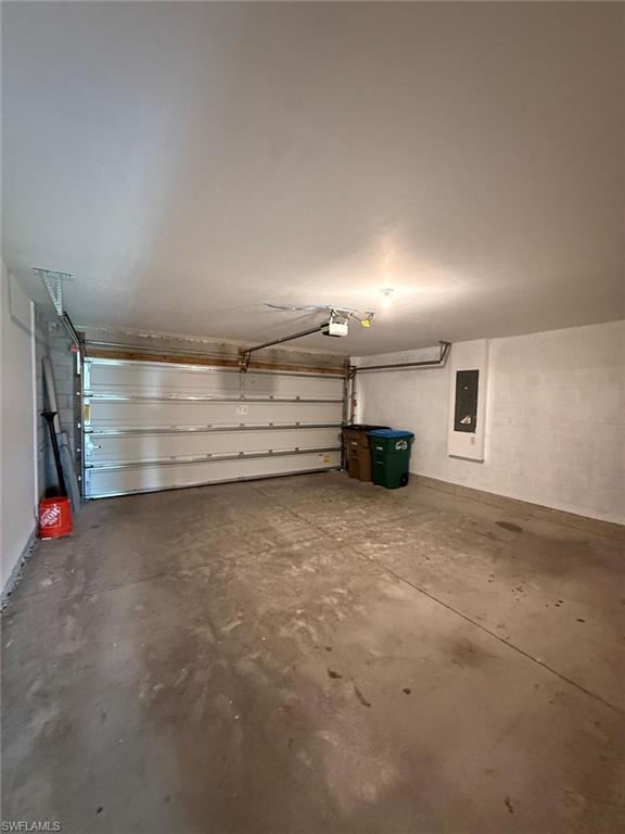 Spacious garage featuring a concrete floor, overhead lighting, and an automatic garage door opener