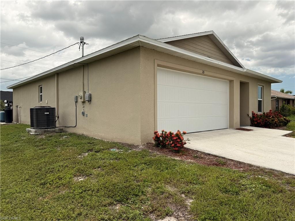 Attached garage with a white panel door, stucco exterior, and concrete driveway