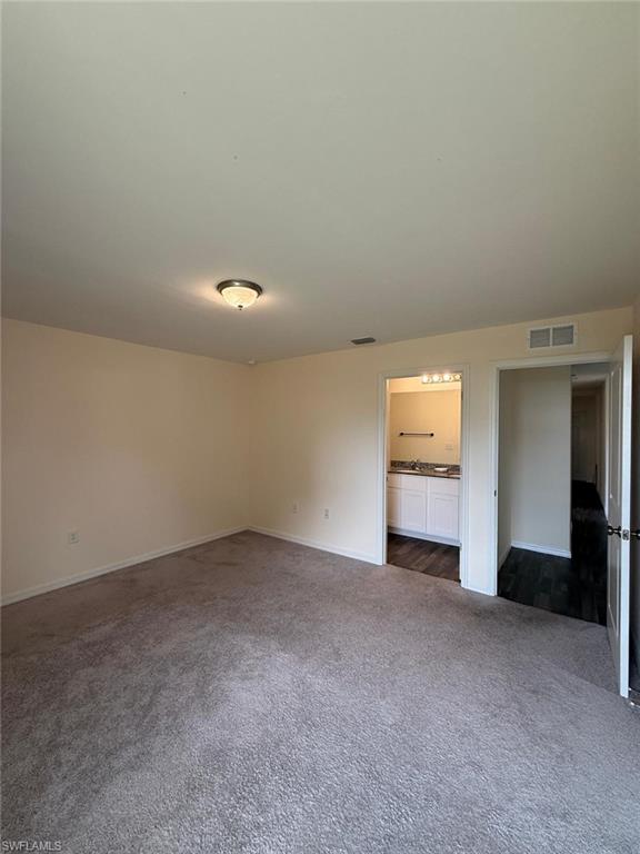 Spacious room with gray carpet flooring and neutral wall tones