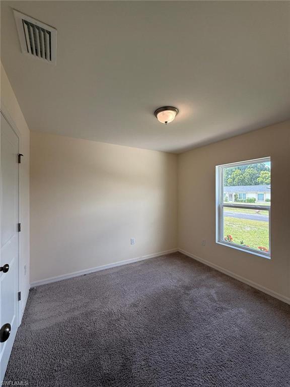 Carpeted room featuring a white paneled door with black hardware, a single window, and a flush-mount ceiling light fixture