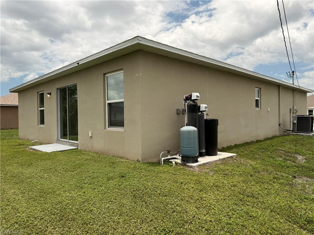 Stucco exterior with a sliding glass door, multiple windows, and exterior lighting