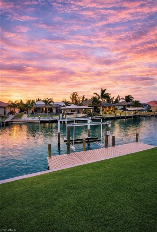 Waterfront property featuring a private boat dock with lift, direct canal access, and a manicured lawn (Rendered photo)