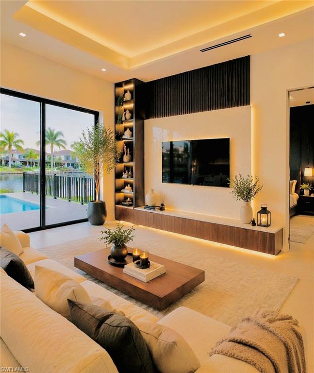 Spacious living area featuring a coffered ceiling with recessed lighting, an integrated entertainment center with wood-finish cabinetry and accent lighting, and a built-in illuminated shelving unit (Rendered photo)