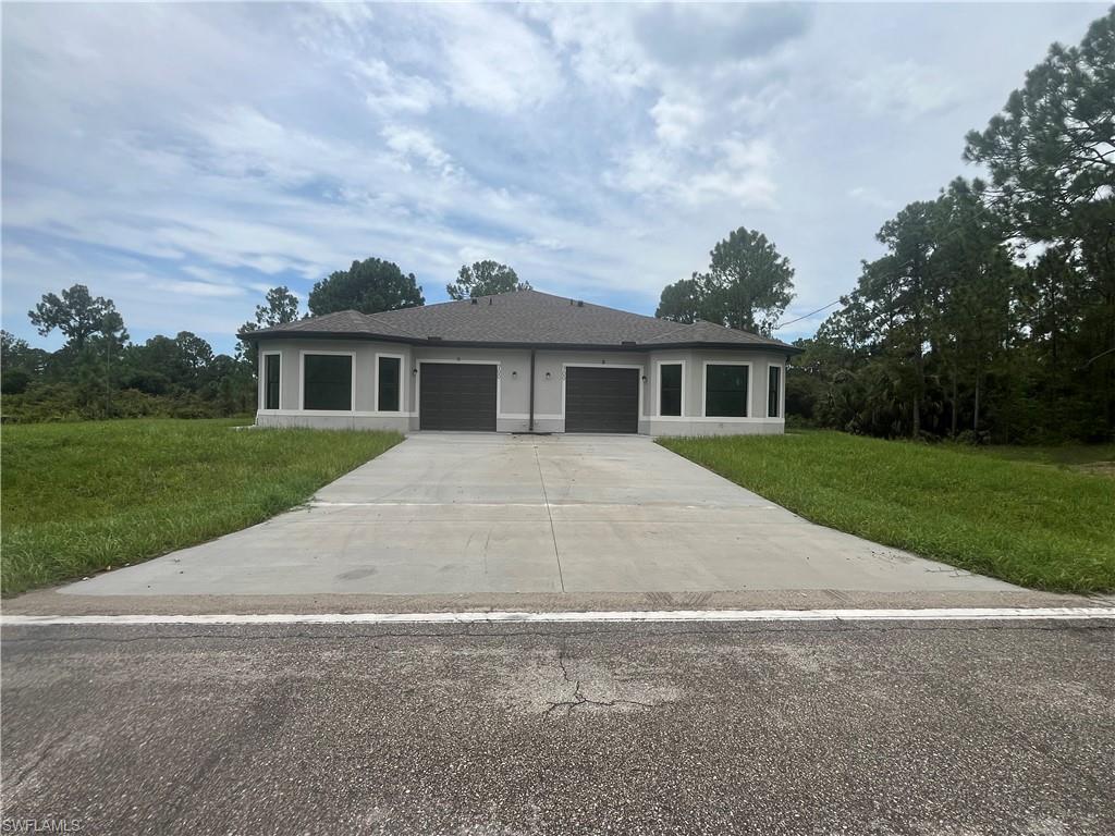 Modern dual-garage residence featuring a clean architectural design with symmetrical facades, white trim detailing, and charcoal garage doors