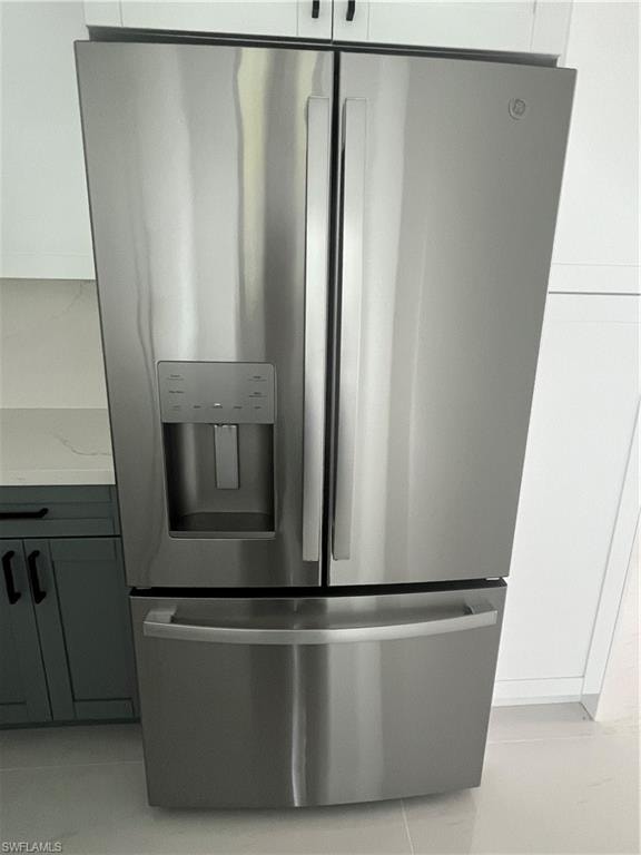 Stainless steel French door refrigerator with dual ice and water dispenser, featuring a spacious bottom freezer drawer and modern handle design