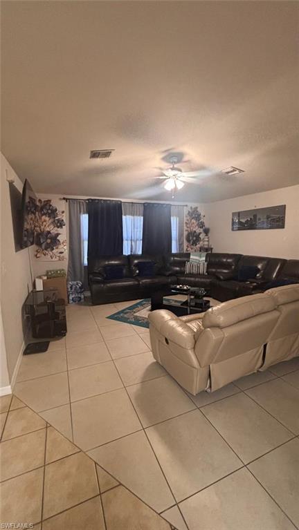 Expansive living area featuring light-toned square floor tiling and a ceiling fan with integrated lighting