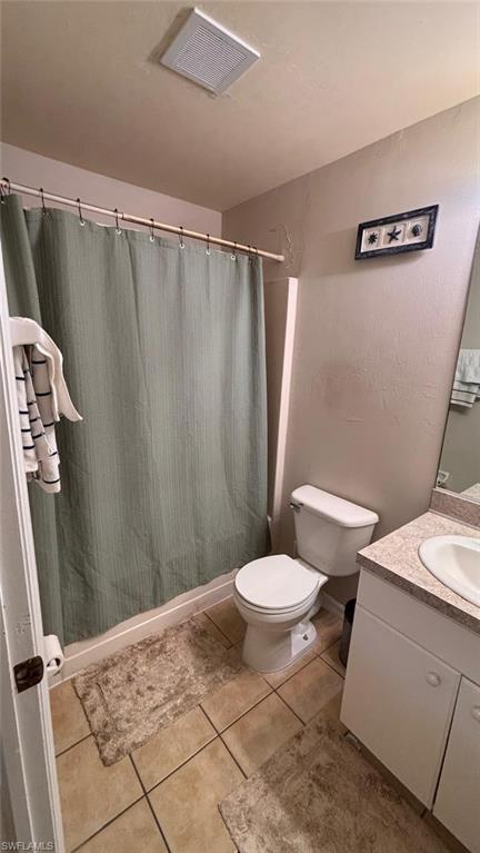 Bathroom featuring a built-in shower, standard toilet, single vanity with integrated sink, and tiled flooring