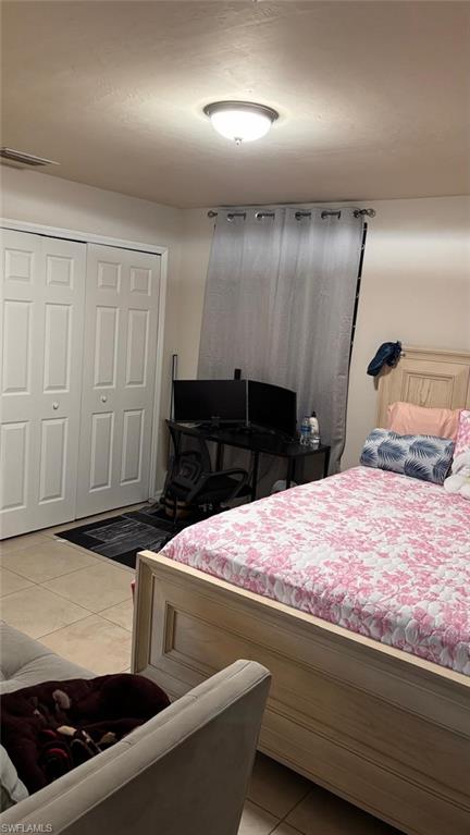 Interior room featuring tile flooring, white bi-fold closet doors, and an overhead flush-mount light fixture