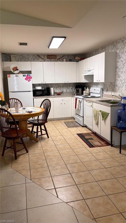 Kitchen featuring white cabinetry, light-toned countertops, and a full suite of white appliances