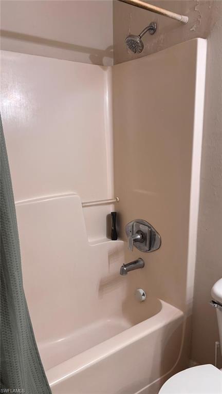 Bathtub and shower combination featuring a built-in shelf, chrome fixtures, and an integrated showerhead