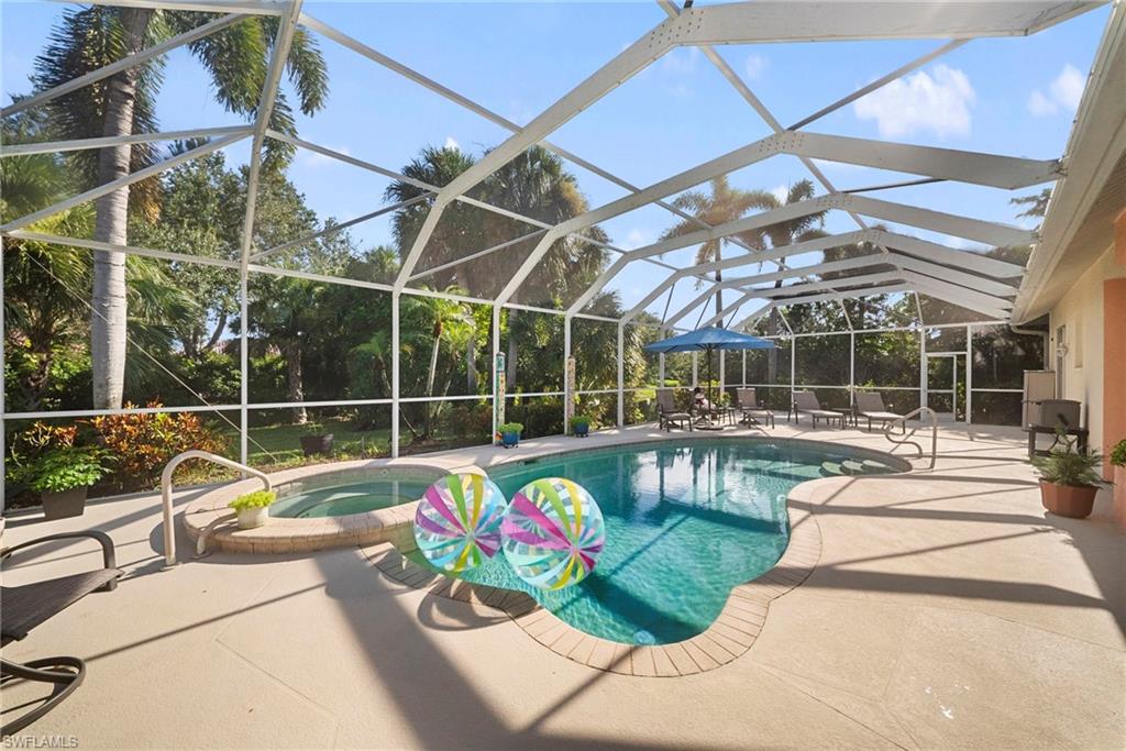 Screened outdoor area featuring a freeform swimming pool, integrated spa, and expansive concrete decking