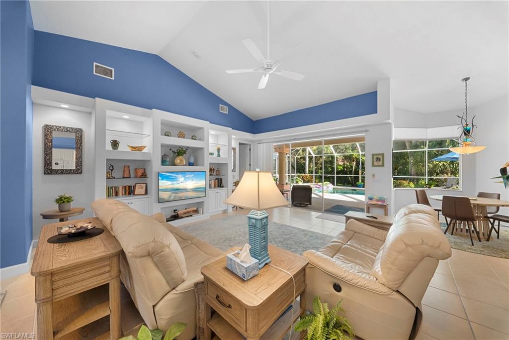 Vaulted ceiling with a ceiling fan, built-in shelving, tile flooring, screened-in patio, and a swimming pool
