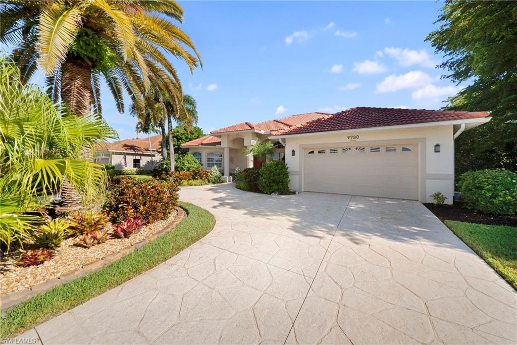 Stucco exterior with a terracotta tile roof, an attached two-car garage, and a stamped concrete driveway