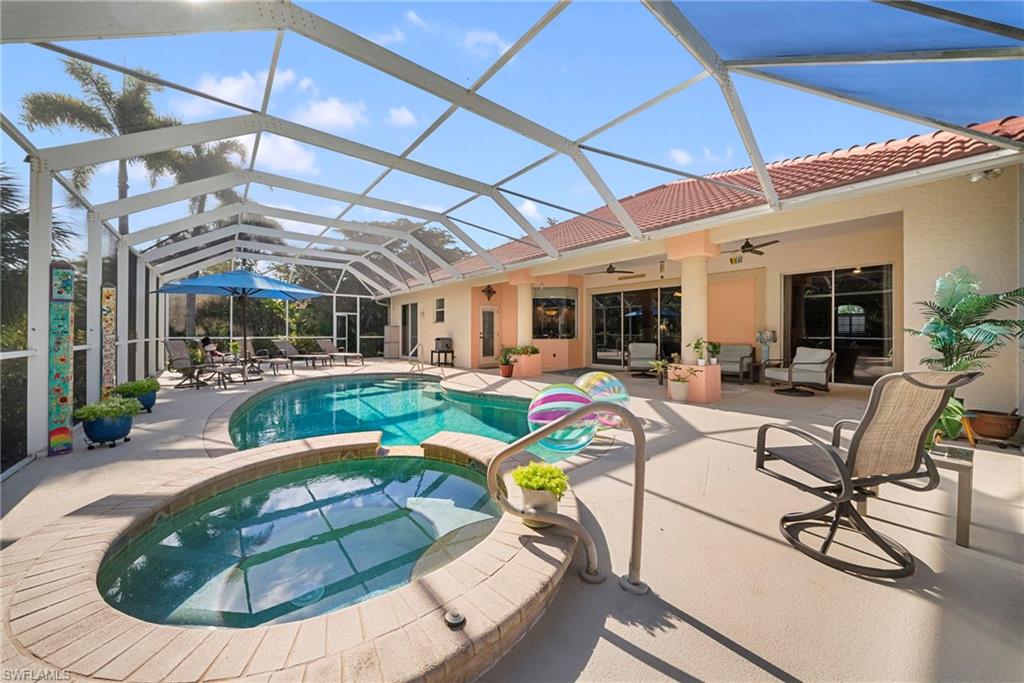 Screened lanai featuring a curved swimming pool, integrated spa with stone coping, and a covered patio area with ceiling fans
