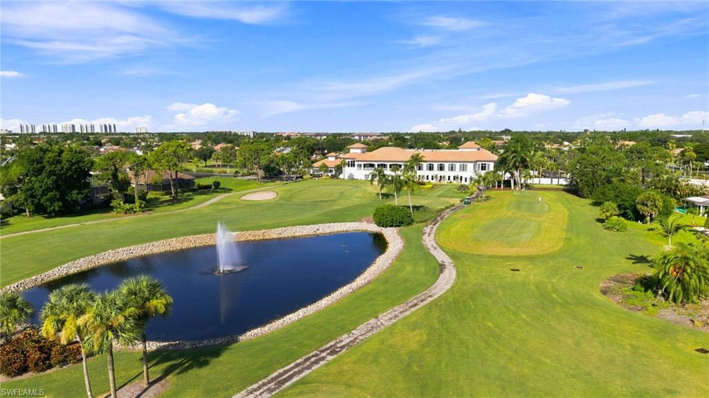 Expansive golf course setting featuring a water feature with a fountain, manicured greens, and mature palm trees