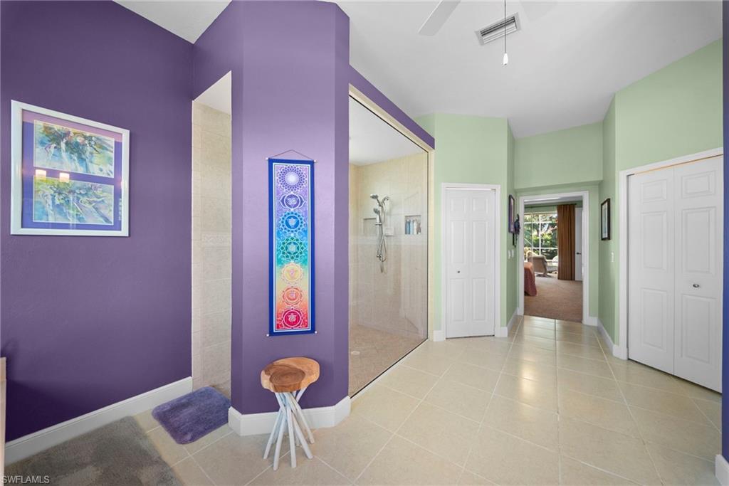 Spacious bathroom featuring a glass-enclosed shower, neutral tile flooring, and vaulted ceilings