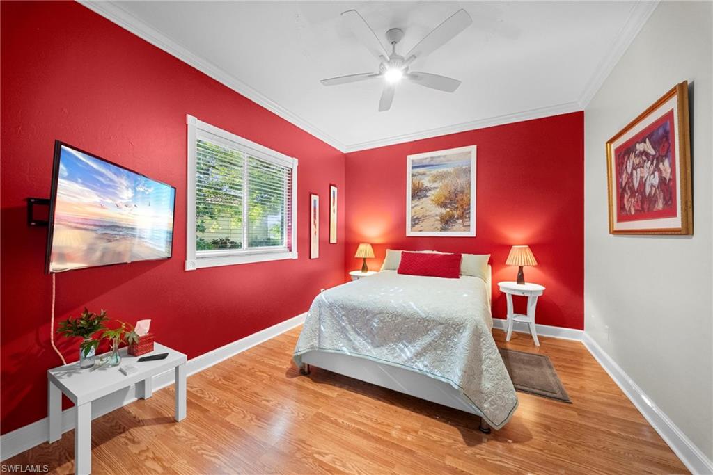 Wood-finish flooring, white crown molding, and a white ceiling fan with integrated lighting