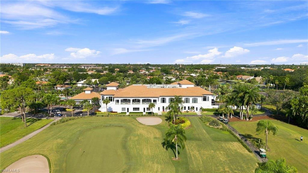 Clubhouse building with a barrel-tile roof, expansive green spaces, mature landscaping, and golf course access