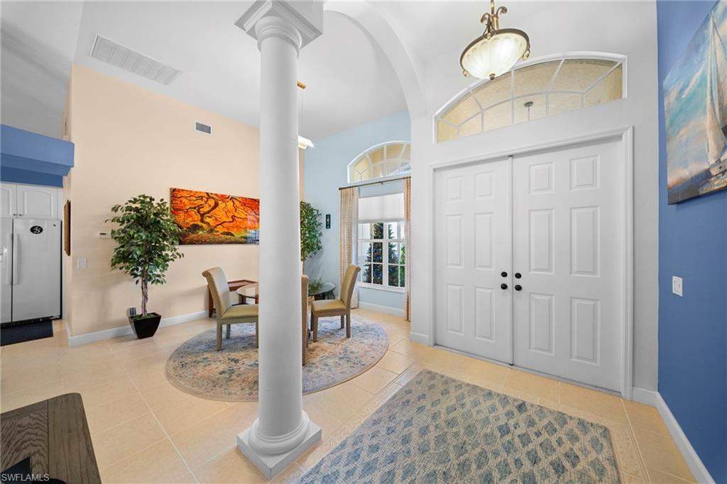 Arched entryway with a prominent column, white paneled double doors, and an arched transom window