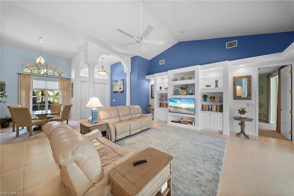 Vaulted ceilings, custom built-in shelving, tile flooring, and a decorative archway