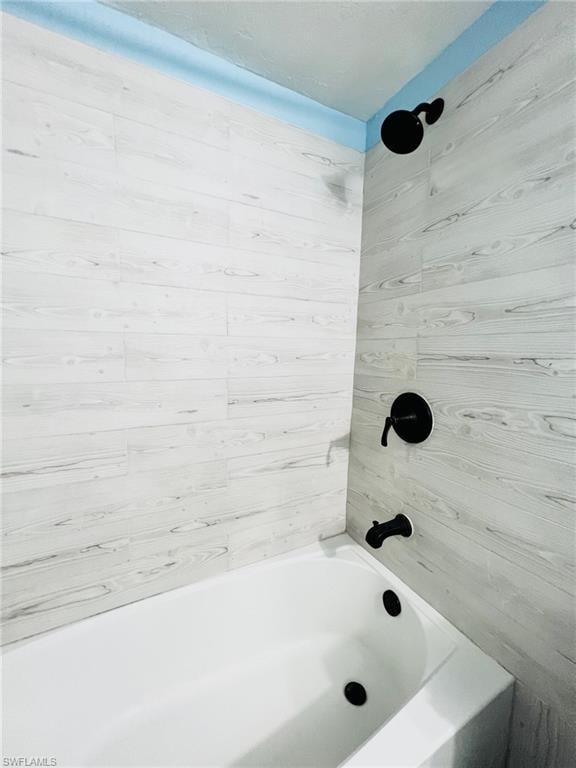 White subway tile surround featuring a matte black shower head, single-handle faucet, and tub filler