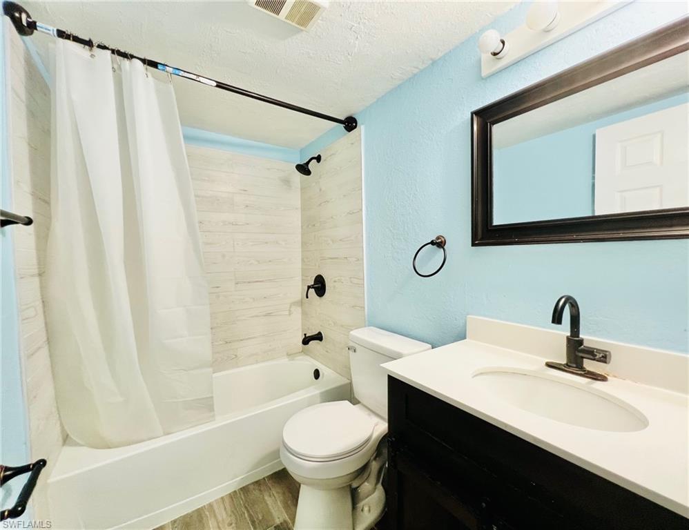 Bathroom featuring a tub/shower combination with light-toned horizontal tile surround and matte black fixtures