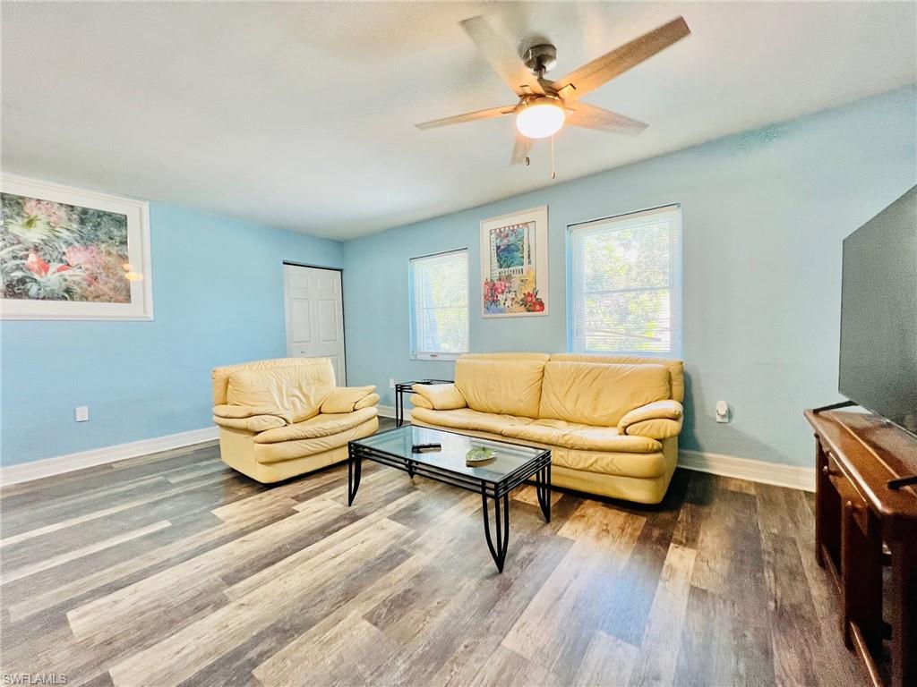 Spacious room featuring wood-finish flooring, light blue walls, and a ceiling fan with integrated lighting