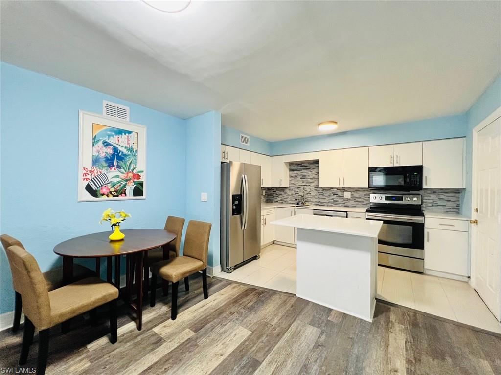 Kitchen featuring white cabinetry, stainless steel appliances, a tiled backsplash, and a central island