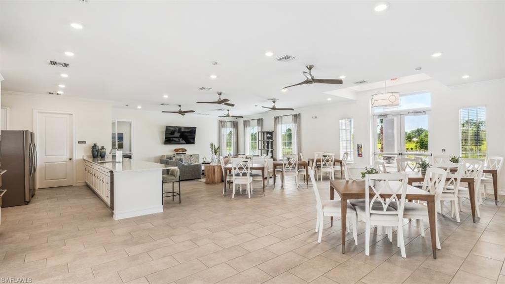 Spacious open-concept interior featuring light-toned tile flooring, recessed lighting, ceiling fans, and an expansive kitchen island with a light-colored countertop