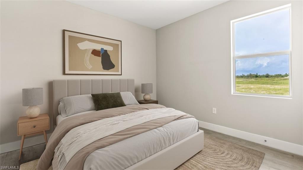 Neutral tone walls with a large window, wood-finish flooring, and a plush upholstered headboard