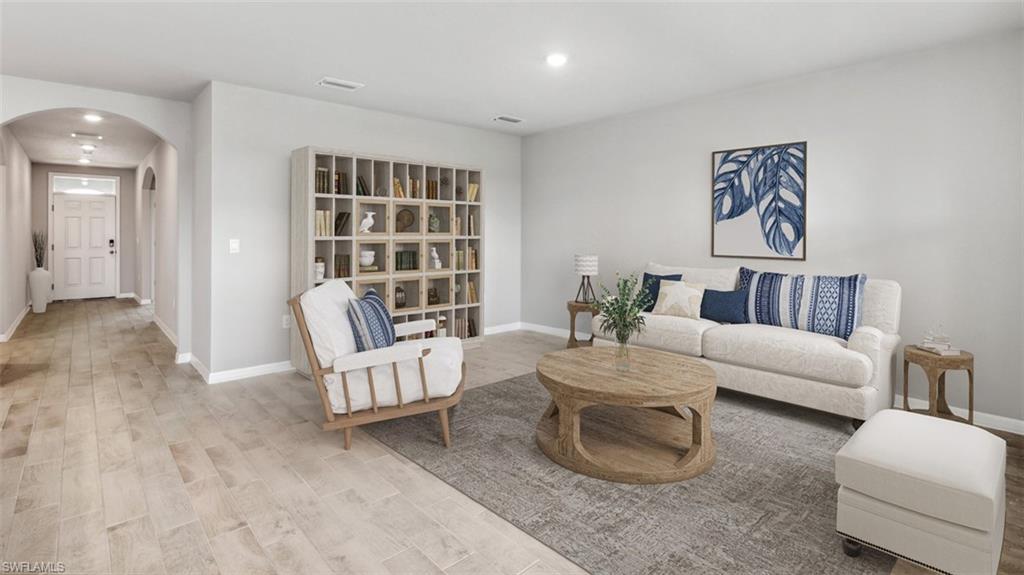 Spacious living area featuring light-toned walls, recessed lighting, and wood-finish flooring
