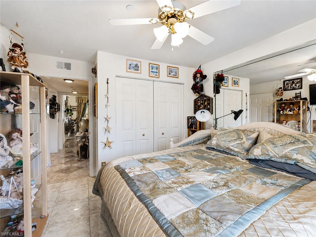 Bedroom featuring neutral tone tile flooring, a ceiling fan with integrated lighting, and white bi-fold closet doors