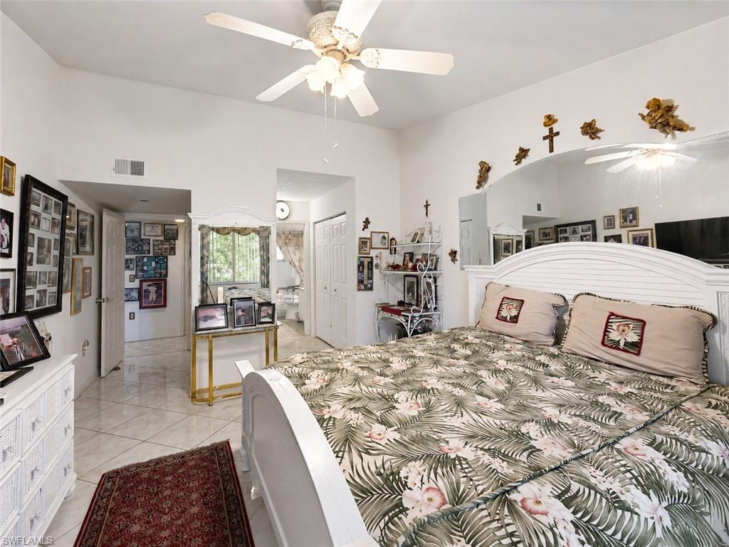 Room featuring white tile flooring, a white ceiling fan, and a built-in arched alcove with a mirrored back wall